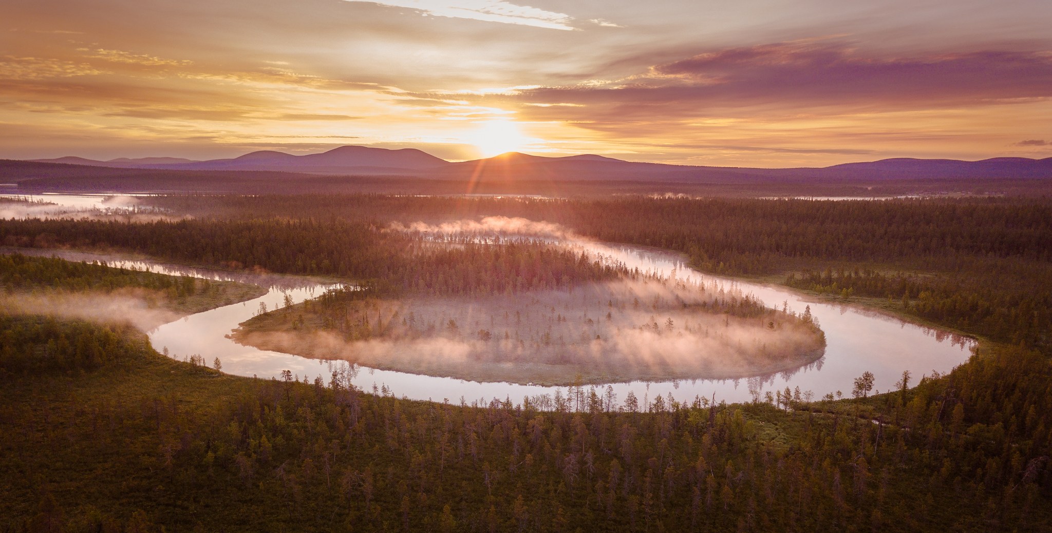 Aerial photo of a summer midnight sun landscape with a foggy river bend in Muonio, Finnish Lapland