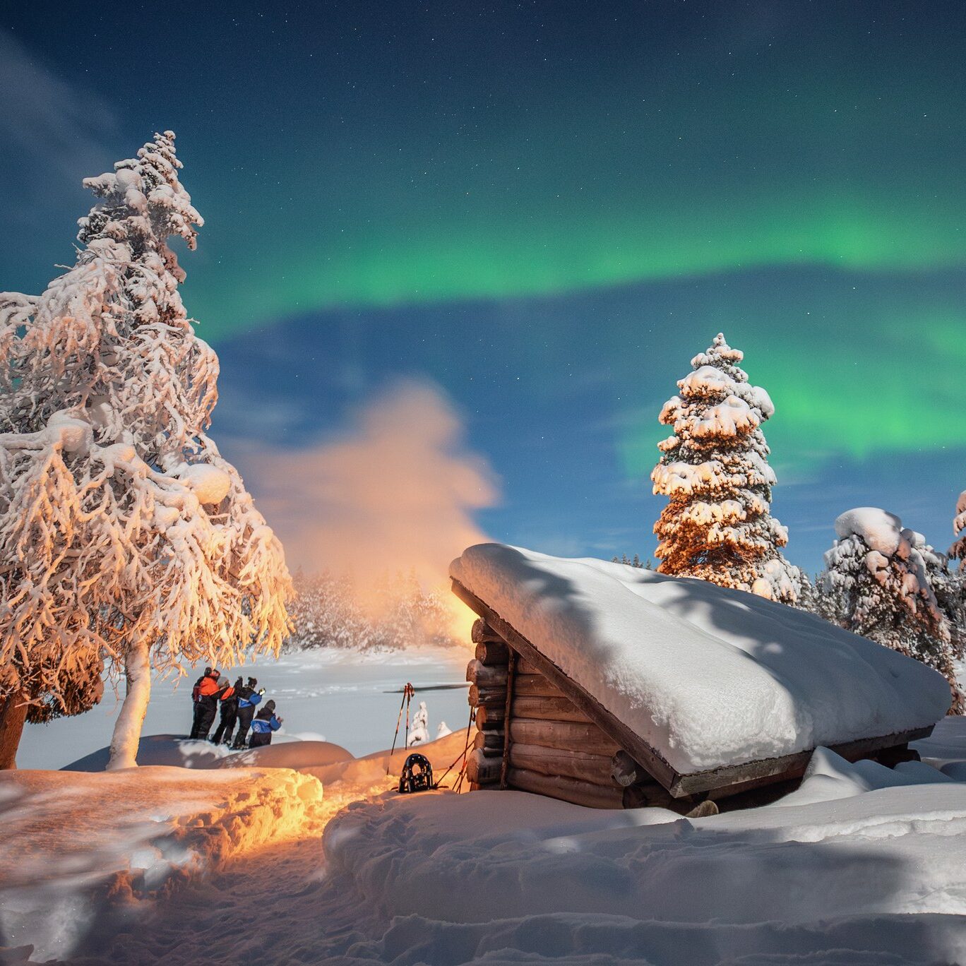Guests enjoying aurora display at a wilderness hut in Lapland Finland by Harriniva Hotels & Safaris