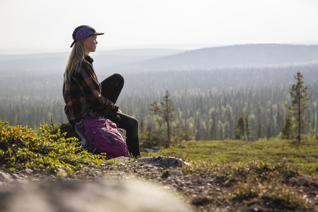 FI: Nainen istuu tunturin rinteellä ja katsoo yli metsäisen Lapin maiseman kesävaelluksella. Harriniva Hotels & Safaris tarjoaa kesäloman Lapissa rauhallisten maisemien, luonnon ja retkien keskellä.
EN: A woman sits on a fell hillside overlooking Lapland’s forest landscape during a summer hike. Harriniva Hotels & Safaris offers a summer holiday in Lapland surrounded by peaceful views, nature, and outdoor adventures.